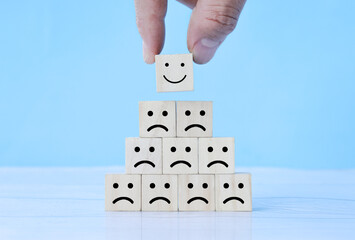 Customer pressing smiley face emoticon on wood cube, Service rating, satisfaction concept.
