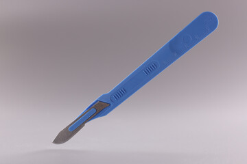 Medical scalpel with blue handle on gray background