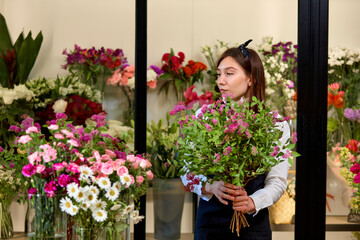Caucasian young woman florist with flowers. Flower's business. Lifestyle flower shop.Flower's shop. Caucasian experienced florist female with beautiful spring flower composition for sale.