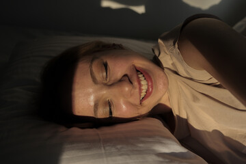 woman falling asleep in her white covered bed, newly awakened blonde woman lying down smiling, newly awakened blonde woman lying down smiling