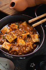 Close-up of mapo tofu or chinese spicy dish made of tofu cubes, ground pork and sichuan peppercorns, vertical shot