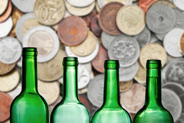 Alcohol price background. Wine bottle excise. Increasing high alcohol tax. Empty bottles with coins in the background.