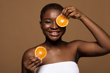 Fruit Acid Peel. Portrait of happy black lady holding two orange slices