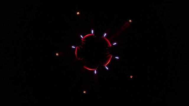Aerial ascending drone footage of an abstract and colourful circle led lights show placed in a fountain in Bratislava, Slovakia. Red and white lights are pulsating and form a star and a circle.
