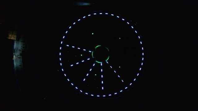 Aerial ascending drone footage of an abstract and colourful circle led lights show placed in a fountain in Bratislava, Slovakia. White, red and blue lights are pulsating in a circular and star shape.