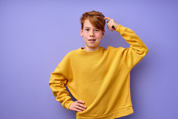 Portrait of pensive teen boy isolated on purple background. Thoughtful teenager holding hand on...