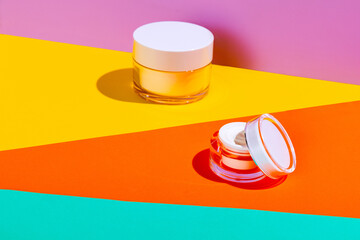 Jars of facial cosmetic cream with copy space for your brand isolated on bright colored background....