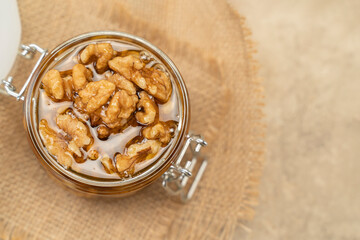 Walnuts in honey close-up. Jar of honey and nuts on a wooden background. Sweet and healthy eating dessert rich in nutrient