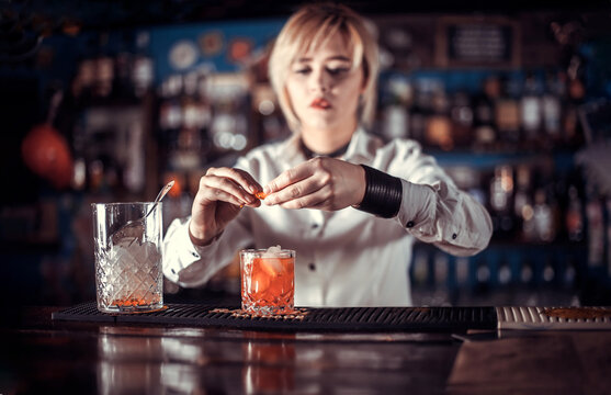Expert woman tapster intensely finishes his creation on the bar