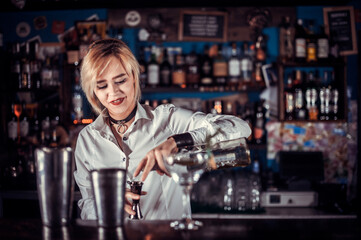 Girl bartender mixes a cocktail on the bar