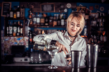 Girl bartender mixes a cocktail on the bar