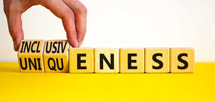 Inclusiveness and uniqueness symbol. Businessman turns wooden cubes, changes words inclusiveness to uniqueness. Beautiful white background. Business, inclusiveness and uniqueness concept. Copy space.