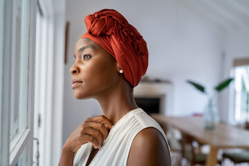 Thoughtful african woman thinking while looking outside the window - obrazy, fototapety, plakaty