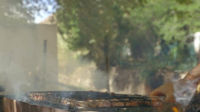 slow motion man turning meat on a barbeque at 60fps