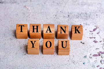 Thank you word written on wooden cubes on gray textured background 
