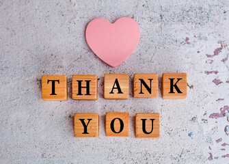 Thank you word written on wooden cubes with pink heart sticky note 