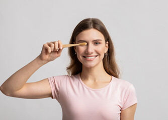 Eco Living Concept. Happy beautiful young woman holding natural wooden bamboo toothbrush