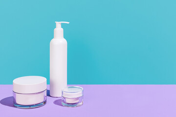 Skincare, bodycare beauty product in white plastic pots for cosmetics without logos isolated over pink and blue background.
