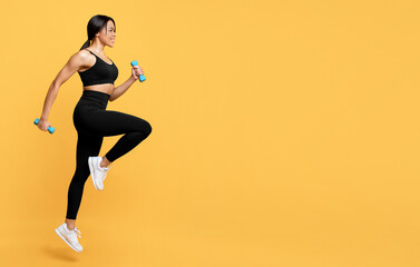 Fototapeta na wymiar Sport exercises concept. Young african american woman exercising with two dumbbells, yellow studio background