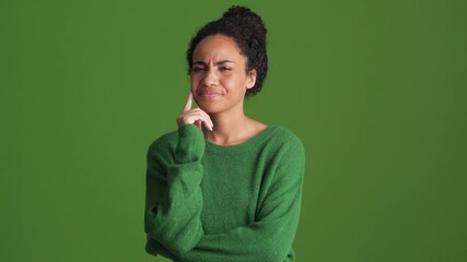 Displeased African woman in green shirt giving negative answer in the green studio