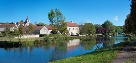 Fototapeta na wymiar Dorfansicht von Saint-Vinnemer am Canal-de-Bourgogne, Panorama mit Reflexion auf ruhigem Wasser