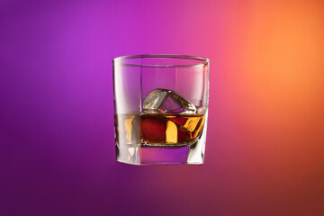 Close-up glass of whiskey isolated over gradient purple and orange color background in neon. Concept of alcohol, holidays