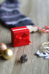 Wool stocking with small presents and Christmas decorations on wooden background. Selective focus.