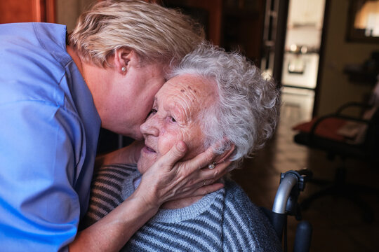 Nurse Hugging Aged Woman In Room