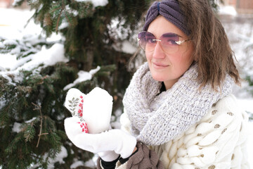 Portrait of a girl on the background of a Christmas tree. She holds a mug with snow in her hands.