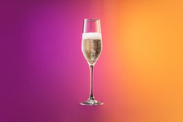 Glass with cold champagne with bubbles isolated over gradient purple and orange color background in neon. Concept of alcohol, holidays, New Year