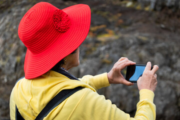 Woman in red hat taking a picture with smartphone