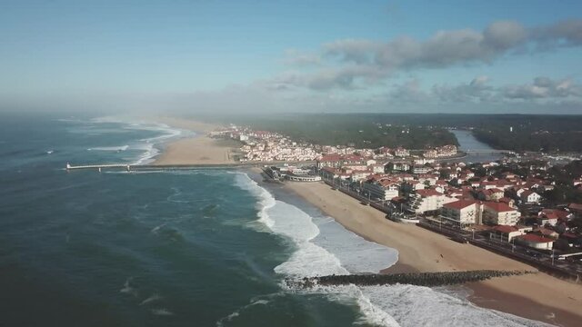 Seaside town of Capbreton in Western France pounded by waves hitting the wave-breaker, Aerial pedestal down shot