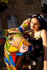 Obraz na płótnie Canvas Portrait of a girl with a bull statue on a summer day.