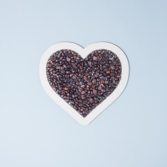 Coffee beans in the shape of a heart on pastel blue background. Banner or advertisement for coffee shop. Flat lay. Copy space