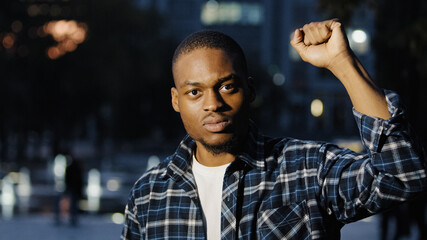 African american man hold fist in air. Social male activist speak outdoors in evening city....