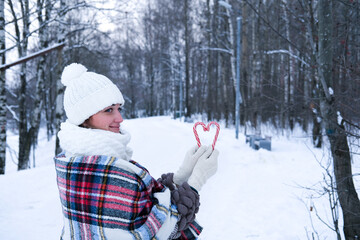 A woman walks through the winter forest, she holds candy canes in her hands.