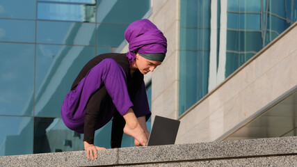 Young strong business woman islamic muslim student stands in balance handstand asana acrobatic...
