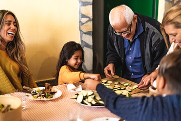 Happy Latin family having fun while preparing dinner together at home - Children spending time with...