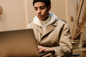 Middle eastern man working with laptop while sitting in cafe