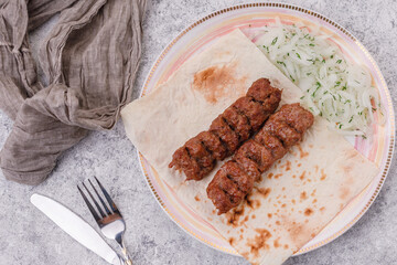 lula kebab on pita bread with pickled onions.