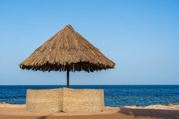 Luxury sand beach with beach chairs and straw umbrellas in tropical resort in Red Sea coast in Egypt, Africa