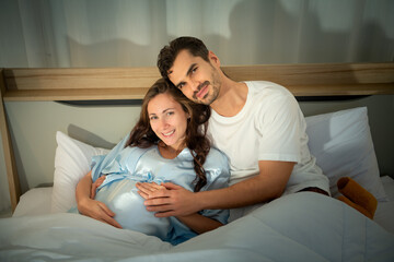 Pregnant woman with husband in bedroom with the atmosphere of having fun talking