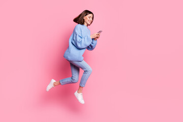 Fototapeta na wymiar Full length body size view of attractive cheerful girl jumping using device chatting isolated over pink pastel color background