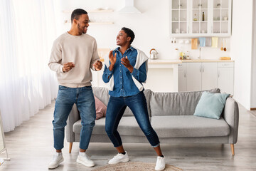 Portrait of joyful afro couple dancing at home