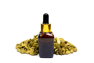 Cardamom essential oil in glass bottle with pile of dry cardamom spice isolated on white background.