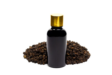 Black pepper essential oil in glass bottle with pile of peppercorn isolated on white background.