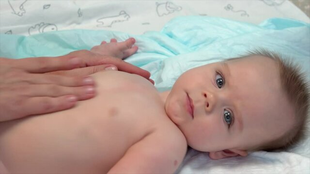 Masseur is making the baby body massage.