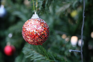 Selective focus on colorful red glitter ball hanging on the Christmas tree with blurred background