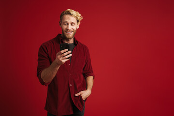 White bearded man wearing shirt smiling and using cellphone