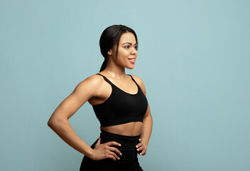 Keep fit. African american woman in sportswear posing and looking aside at free space on blue background, studio shot